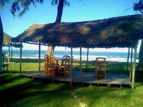 un tavolo e sedie sotto un ombrellone di paglia sulla spiaggia di Chez Zizou Manakara a Manakara