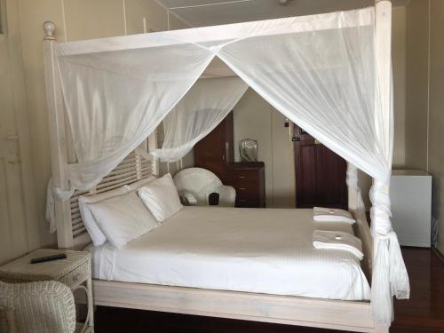 een slaapkamer met een wit bed en een baldakijn bij The Prince of Wales in Proserpine
