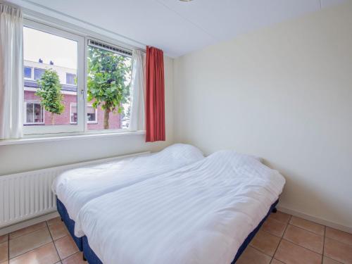 een wit bed in een kamer met een raam bij Holiday Home De Meerparel-7 in Uitgeest
