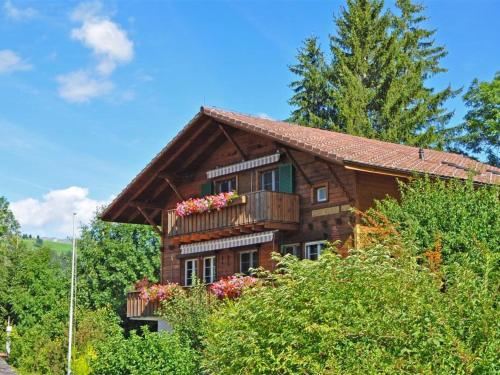 a large wooden house with a balcony and trees at Apartment Christeli by Interhome in Zweisimmen