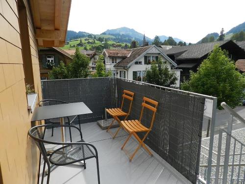 uma varanda com 3 cadeiras, uma mesa e uma cerca em Apartment Simme-Tröimli by Interhome em Zweisimmen