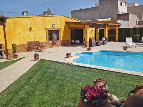 une arrière-cour avec une piscine et un bâtiment jaune dans l'établissement Holiday Home L'Aldea by Interhome, à L'Aldea