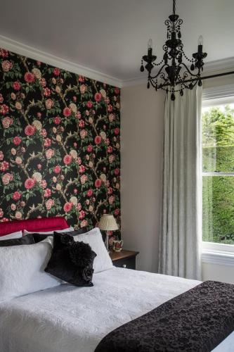 a bedroom with a floral wall with a bed and a window at Laurella Cottage in Blenheim