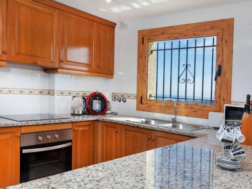 a kitchen with wooden cabinets and a sink and a window at Holiday Home Lausanne by Interhome in Calonge