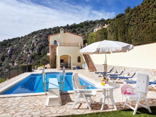 a villa with a swimming pool and a table with an umbrella at Holiday Home Lausanne by Interhome in Calonge