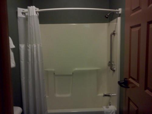 a bathroom with a shower with a white shower curtain at Arrowwood Lodge at Brainerd Lakes in Baxter