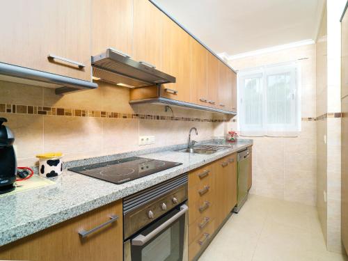 una cocina con armarios de madera y fregadero en Apartment Pinazo by Interhome, en Cumbre del Sol
