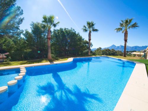 a swimming pool with palm trees and mountains in the background at Apartment Villa Marina Golf-1 by Interhome in Altea la Vieja