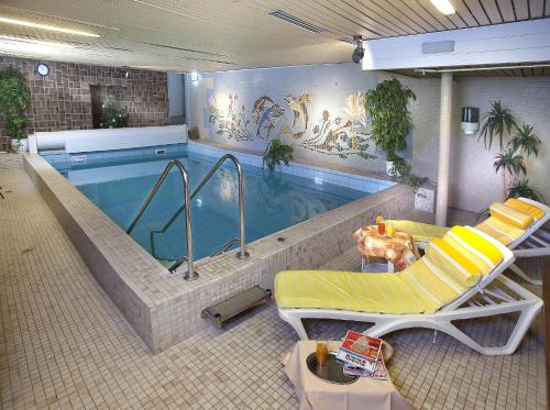 einen Pool mit 2 Liegestühlen und einem Pool in der Unterkunft Hotel Pohl in Kinheim
