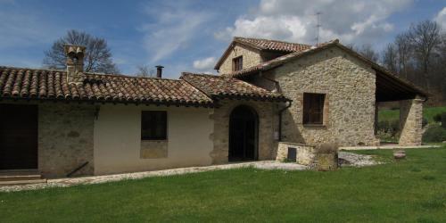 an old stone house with a grass yard at Il Vignale in Massa Martana