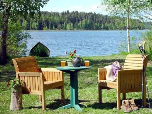 a picnic table with two chairs and a table with a lake at Holiday Home Kopinkallio 1 by Interhome in Vääksy
