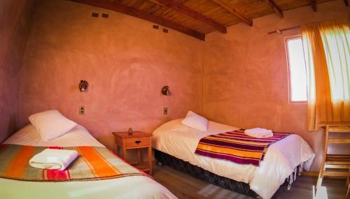 Habitación pequeña con 2 camas y ventana en Sol del Desierto, en Chíuchíu