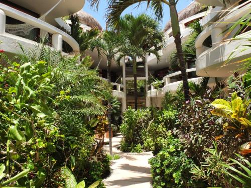 a garden in front of a building with palm trees at Playa Palms Beach Hotel in Playa del Carmen