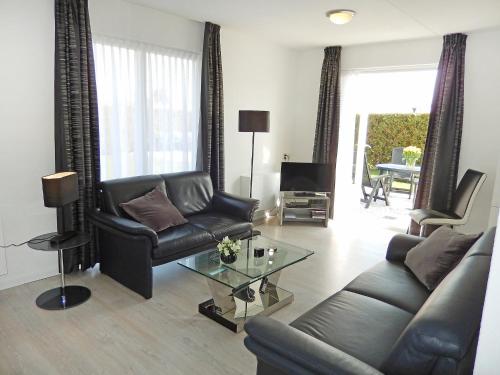 a living room with a leather couch and a table at Holiday Home Plevier Comfort-3 by Interhome in Noordwijkerhout