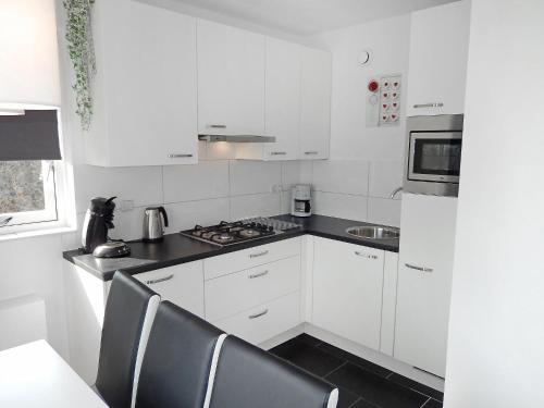 a kitchen with white cabinets and a stove top oven at Holiday Home de Witte Raaf-3 by Interhome in Noordwijkerhout
