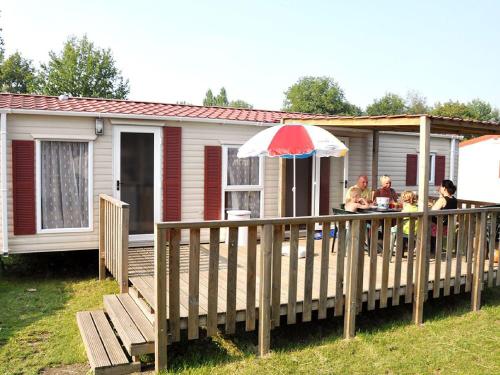 a house with a deck with a table and an umbrella at Holiday Home Prinsenmeer-25 by Interhome in De Beek