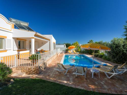 een huis met een zwembad met stoelen en een parasol bij Villa Natura by Interhome in Guia