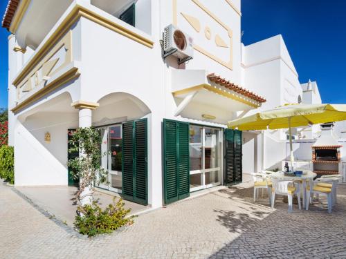 a white house with green shutters and a patio at Holiday Home Manta Rota 450m from the Beach by Interhome in Altura