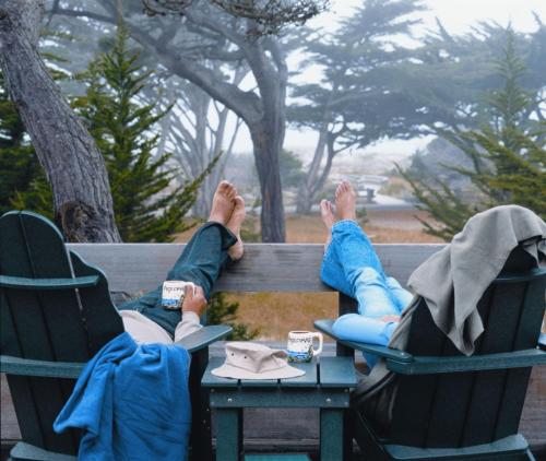 two people sitting on a bench with their feet up at Asilomar Conference Grounds in Pacific Grove