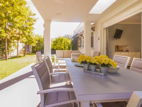 カンブリルスにあるHoliday Home El Dorado Playa Villa La Roca by Interhomeの黄色い花のポーチにテーブルと椅子