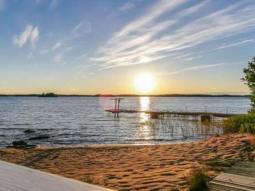 a beach with the sun setting on the water at Holiday Home Hästöskata a by Interhome in Kruunupyy