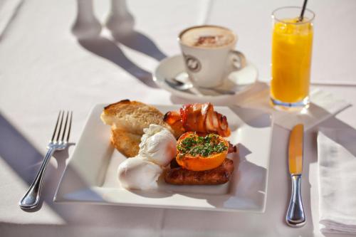 Un plato de desayuno en una mesa con un vaso de jugo de naranja. en Sunseeker Motor Inn, en Batemans Bay