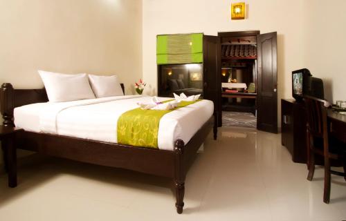 a bedroom with a bed with white sheets and a desk at Bali Ayu Hotel & Villas in Seminyak
