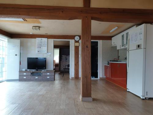 a large living room with a kitchen and a tv at Tongyeong Yehyang Pension in Tongyeong