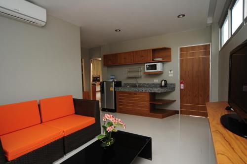 a living room with an orange couch and a kitchen at Phu NaNa Boutique Hotel - SHA Plus in Rawai Beach