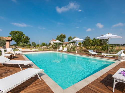 a pool with chairs and umbrellas on a wooden deck at Villa Marina Velca by Interhome in Tarquinia