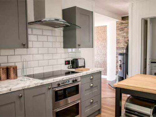 a kitchen with stainless steel appliances and a table at Holiday Home Taobh na Mara by Interhome in Kensaleyre