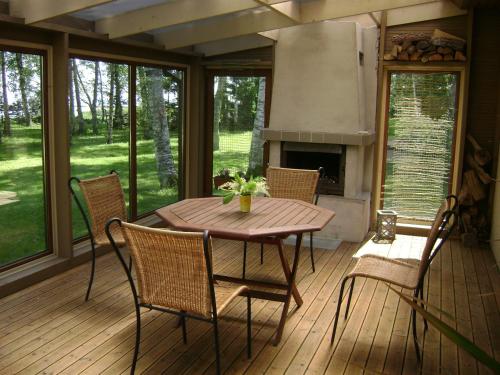 a wooden table and chairs on a porch with a fireplace at Mere Holiday House in Salme