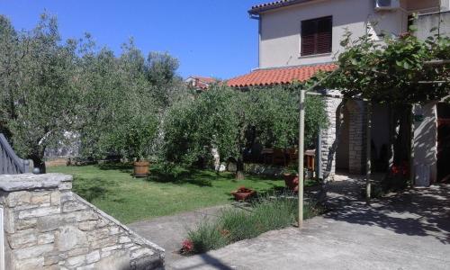un jardín con olivos y una casa en Apartments Anica, en Pula