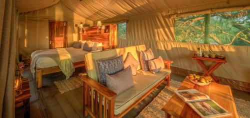 ein Schlafzimmer mit einem Bett und einem Sofa in einem Zimmer in der Unterkunft Xaro Lodge in Shakawe