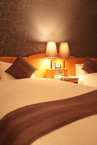 a hotel room with a large bed with two lamps at Okayama Koraku Hotel in Okayama