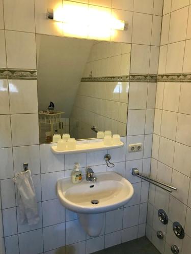 ein weißes Badezimmer mit Waschbecken und Spiegel in der Unterkunft "Matrosenlogis" by Ferienhaus Strandgut in Born