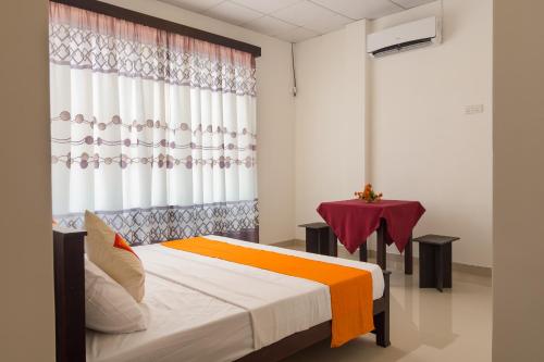 a bedroom with a bed with a curtain and a table at Harry Inn in Negombo