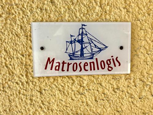 a sign for a ship on a wall at "Matrosenlogis" by Ferienhaus Strandgut in Born