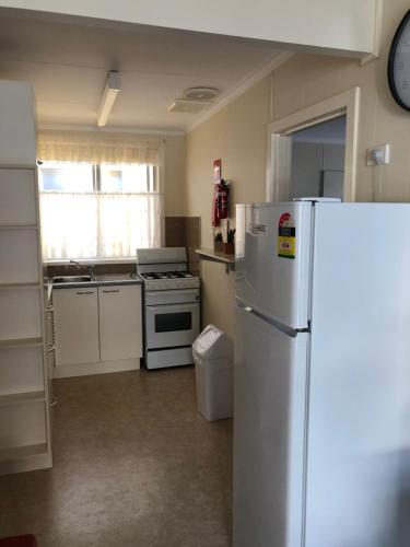 a kitchen with a white refrigerator and a stove at Koonwarra Holiday Park in Lakes Entrance
