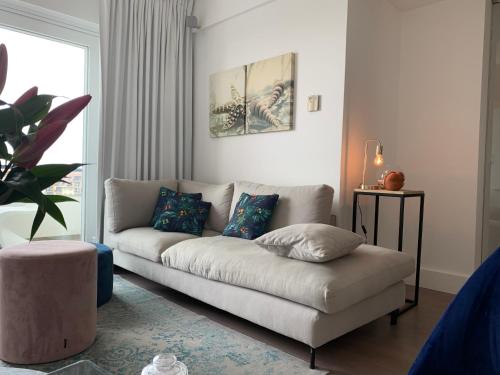 a living room with a white couch with pillows at Koksijde l'Abbaye in Koksijde