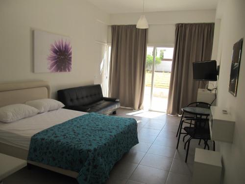 um quarto com uma cama, uma cadeira e uma televisão em Sunny Holiday Apartments em Protaras