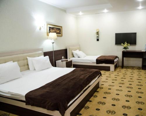 a hotel room with two beds and a television at Luxury House in Shymkent