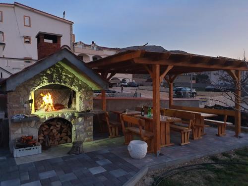 a patio with a stone fireplace and a table and benches at Apartmani Dalmatinka in Metajna