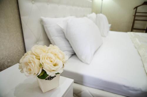 a vase of flowers on a table next to a bed at Luxury House in Shymkent