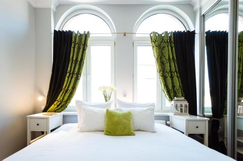 クラクフにあるエンジェル ハウス ベッド & ブレックファーストのベッドルーム1室(白いベッド1台、窓2つ付)