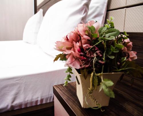 a vase of flowers on a table next to a bed at Luxury House in Shymkent