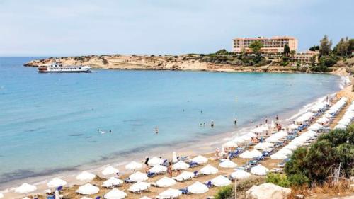 a beach with a bunch of umbrellas and the ocean at VILLA LAMBRIANA in Peyia