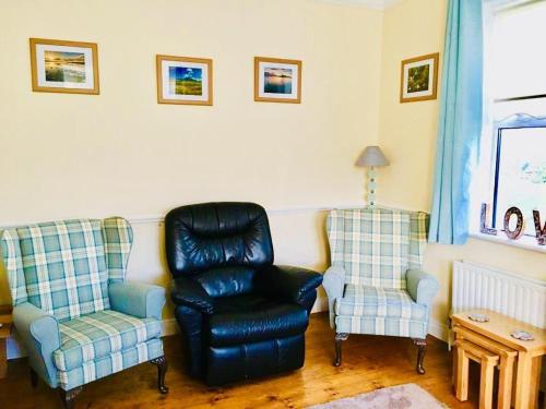 a living room with two chairs and a black chair and a chair at Birch Tree Cottage in Westport