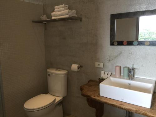 a bathroom with a toilet and a sink and a mirror at Seashore My Home in Eluan