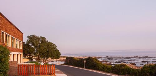 a road next to a building with a view of the ocean at Rots en See in Gansbaai
